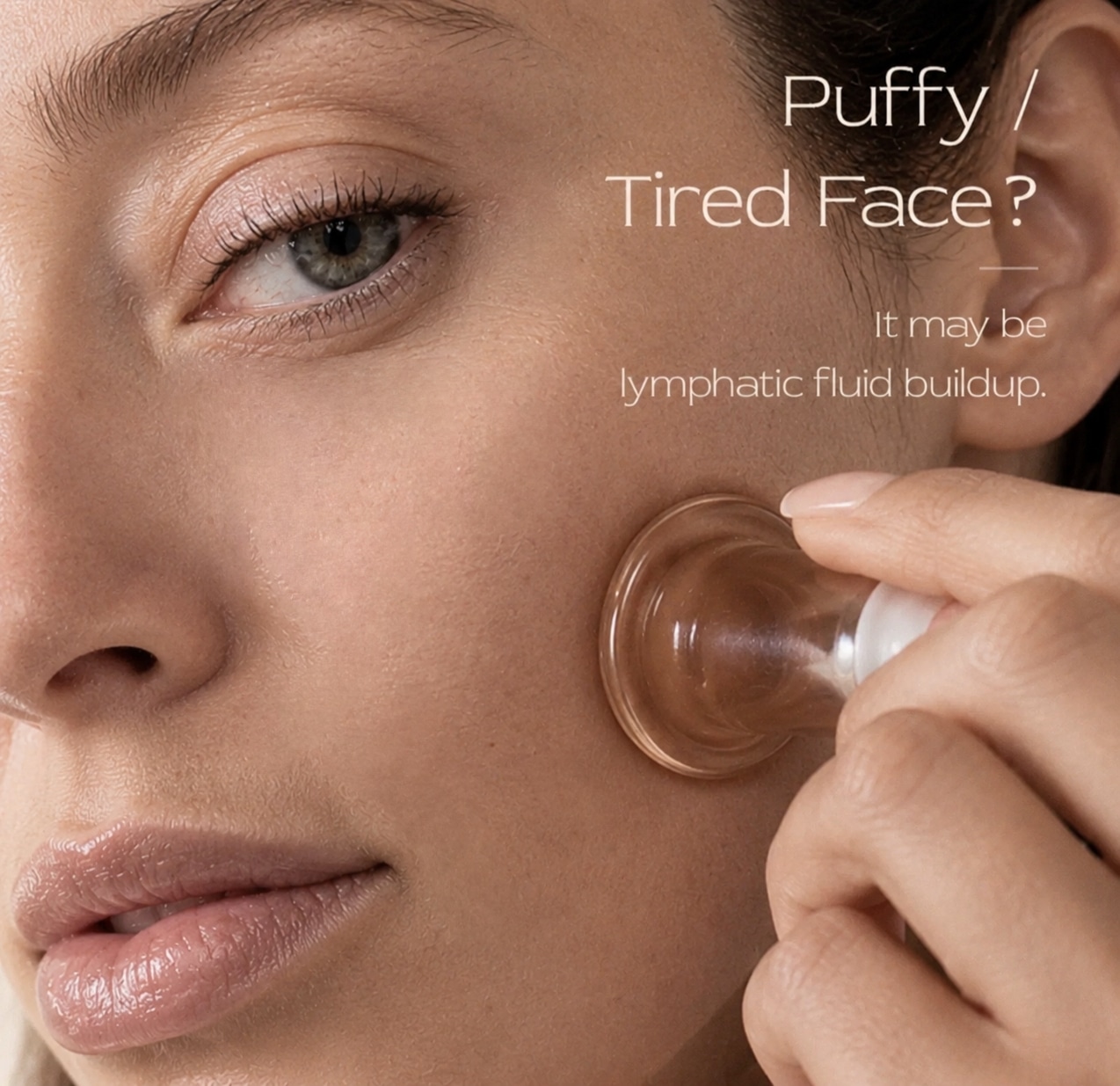 A close-up of a woman using a facial suction tool on her cheek, promoting lymphatic drainage. The background features text asking if the viewer has a puffy or tired face, suggesting it may be caused by lymphatic fluid buildup.